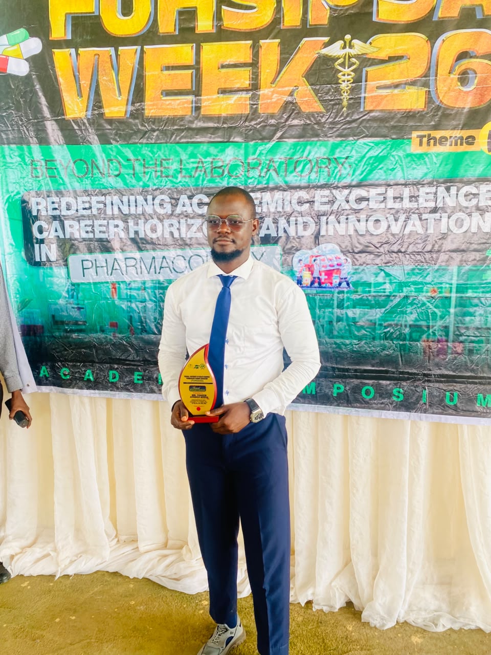 Toheeb Ayodeji Sodiq holding the Award of Excellence at a pharmacology academic symposium